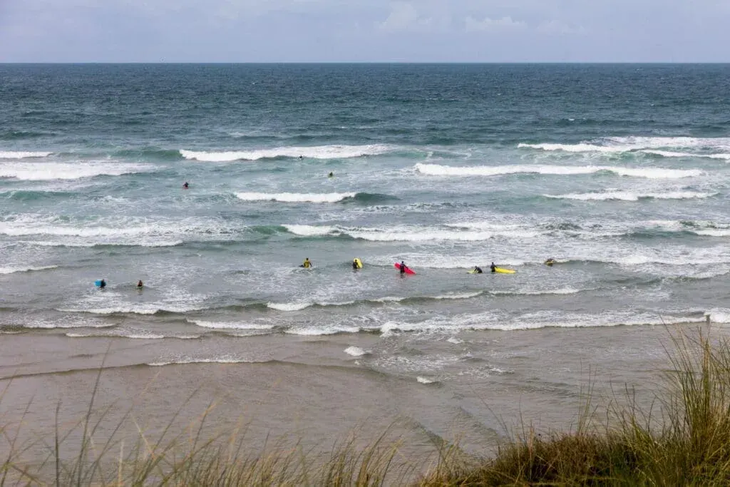 Surfers and swimmers in the sea at Mawgan Porth Beach, North Cornwall