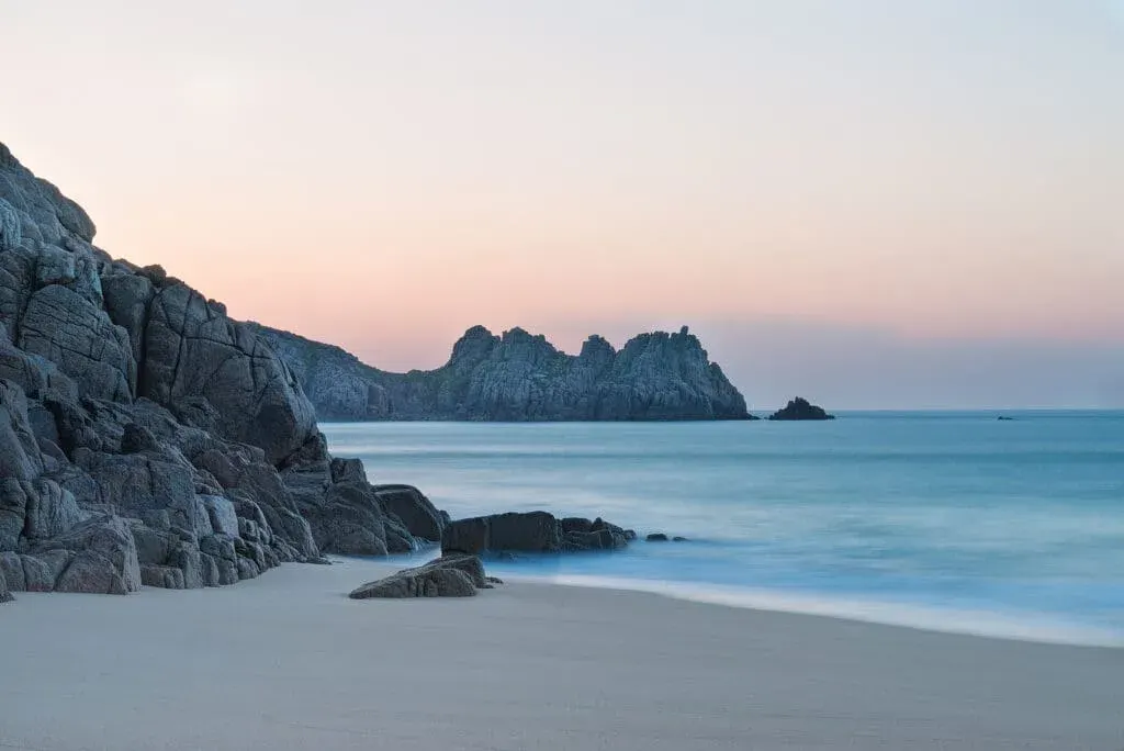 Beautiful colourful sunrise landscape image of Porthcurno Beach, Cornwall