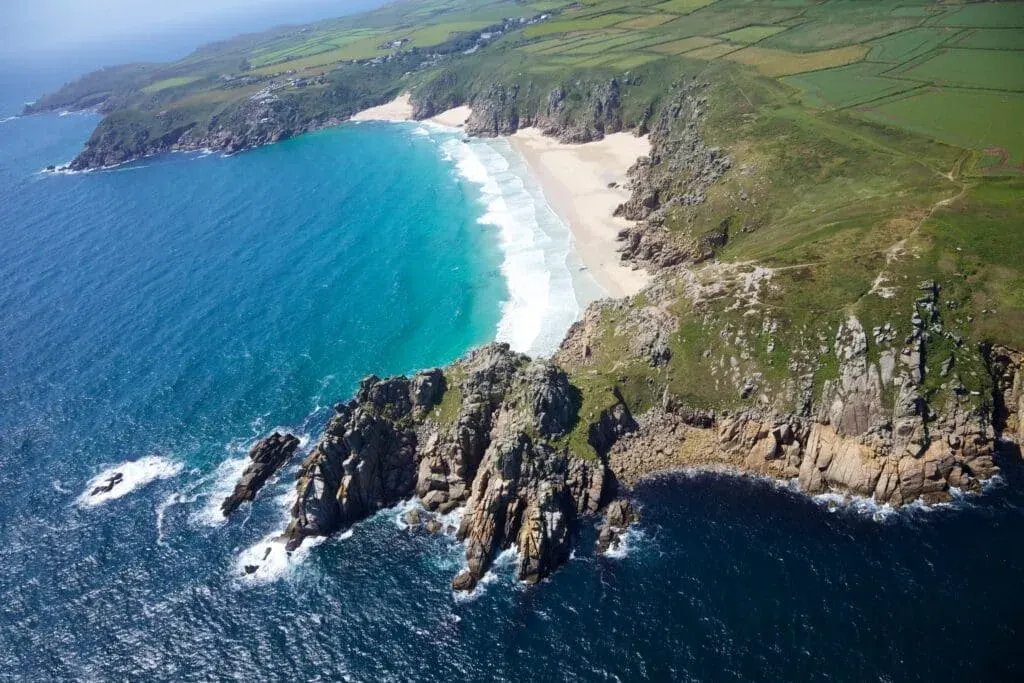 An aerial photo of Treen Cliff and Porthcurno Beach, Cornwall (looking west)