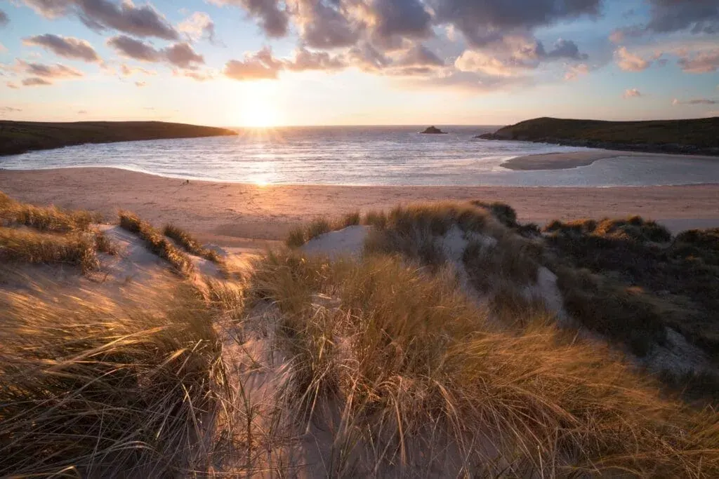 The sun sets over the sand dunes at Crantock Beach, Cornwall